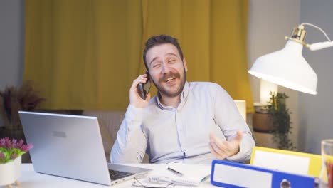 Home-office-worker-man-talking-on-the-phone-happily.